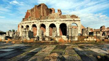 Ancient ruins with multiple arches and columns, set against a clear sky.