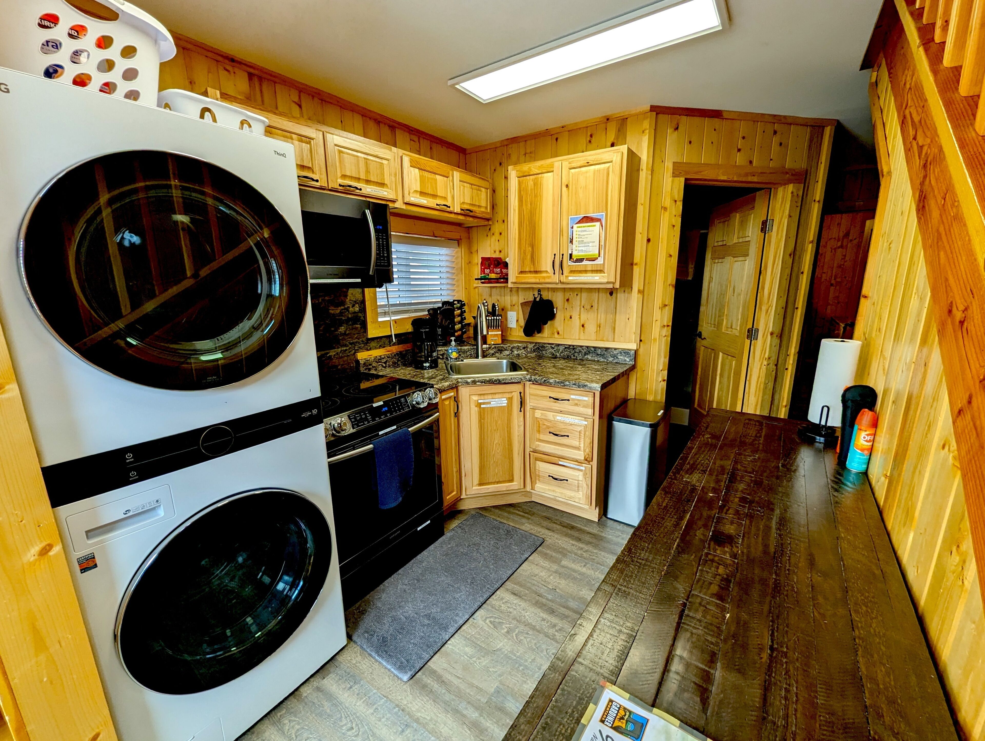 Une cuisine compacte avec des meubles en bois, un lave-linge, un four à micro-ondes et un évier.