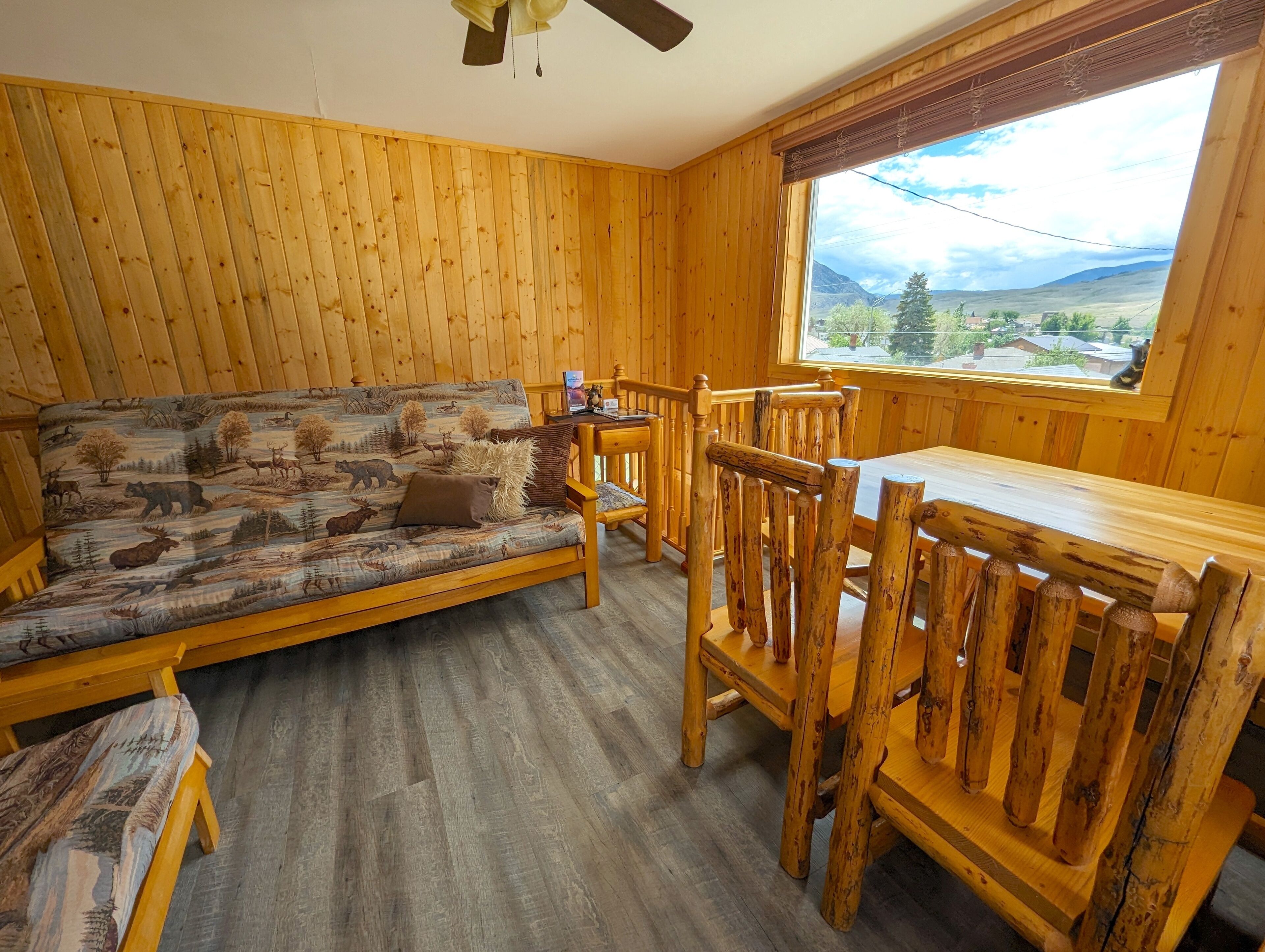 A wooden cabin interior with a sofa, wooden dining table, and chairs.