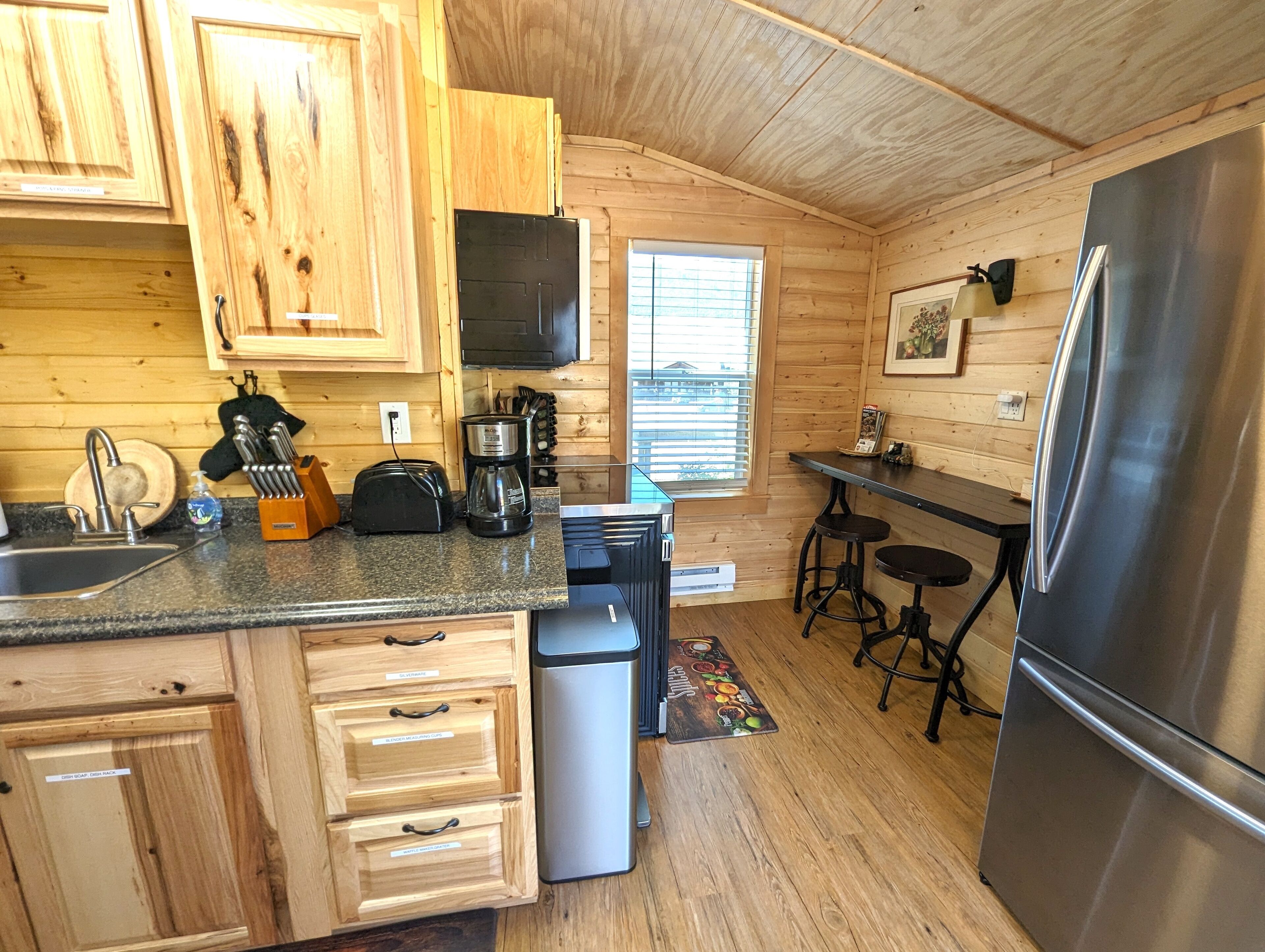 A compact kitchen with wooden cabinets, a stainless steel refrigerator, and a coffee maker.