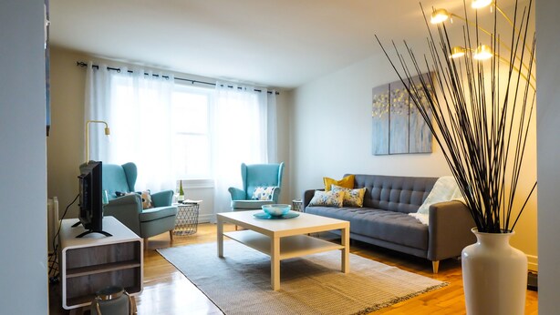 A modern living room with a sofa, two armchairs, a coffee table, and a TV.
