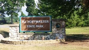 Schild für den P.J. Hoffmaster State Park mit einer Steinmauer und einem Wappen des Ministeriums für natürliche Ressourcen.