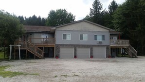 Ein zweistöckiges Haus mit einer Veranda, einer Garage und einem überdachten Balkon.