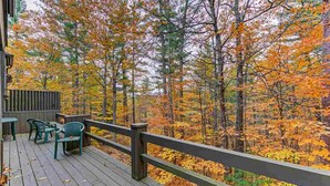 Eine Holzterrasse mit Sitzgelegenheiten und Blick auf einen Herbstwald.