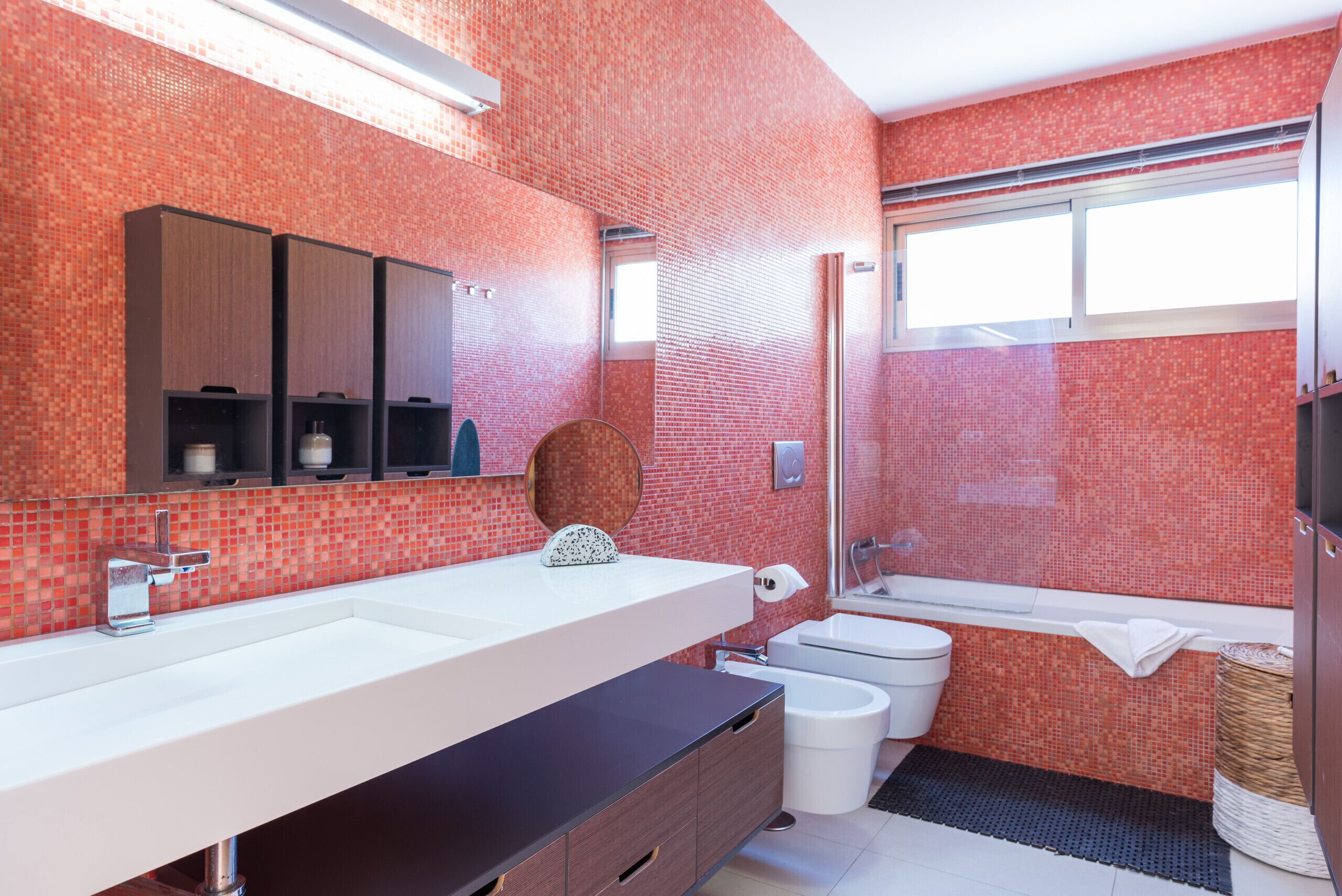 A modern bathroom with a large sink, mirror, and a bathtub.