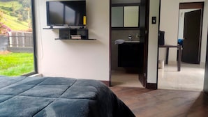 A bedroom with a bed, a TV mounted on the wall, and a view of a garden. - Comfort Campestre (Tabio)