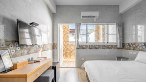 A modern bedroom with a bed, a desk with a computer, a TV, and an air conditioning unit. - Taitung Hope castle (Taitung)