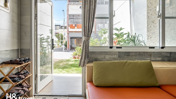A modern living room with a sofa and a shoe rack, a large window with curtains, and a view of the outside. - Taitung Hope castle (Taitung)