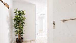Un pasillo con una planta de bambú en maceta, una paleta de madera en la pared y una puerta con manija.
