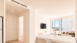 Un apartamento moderno con comedor, televisor montado en la pared y balcón con vistas.