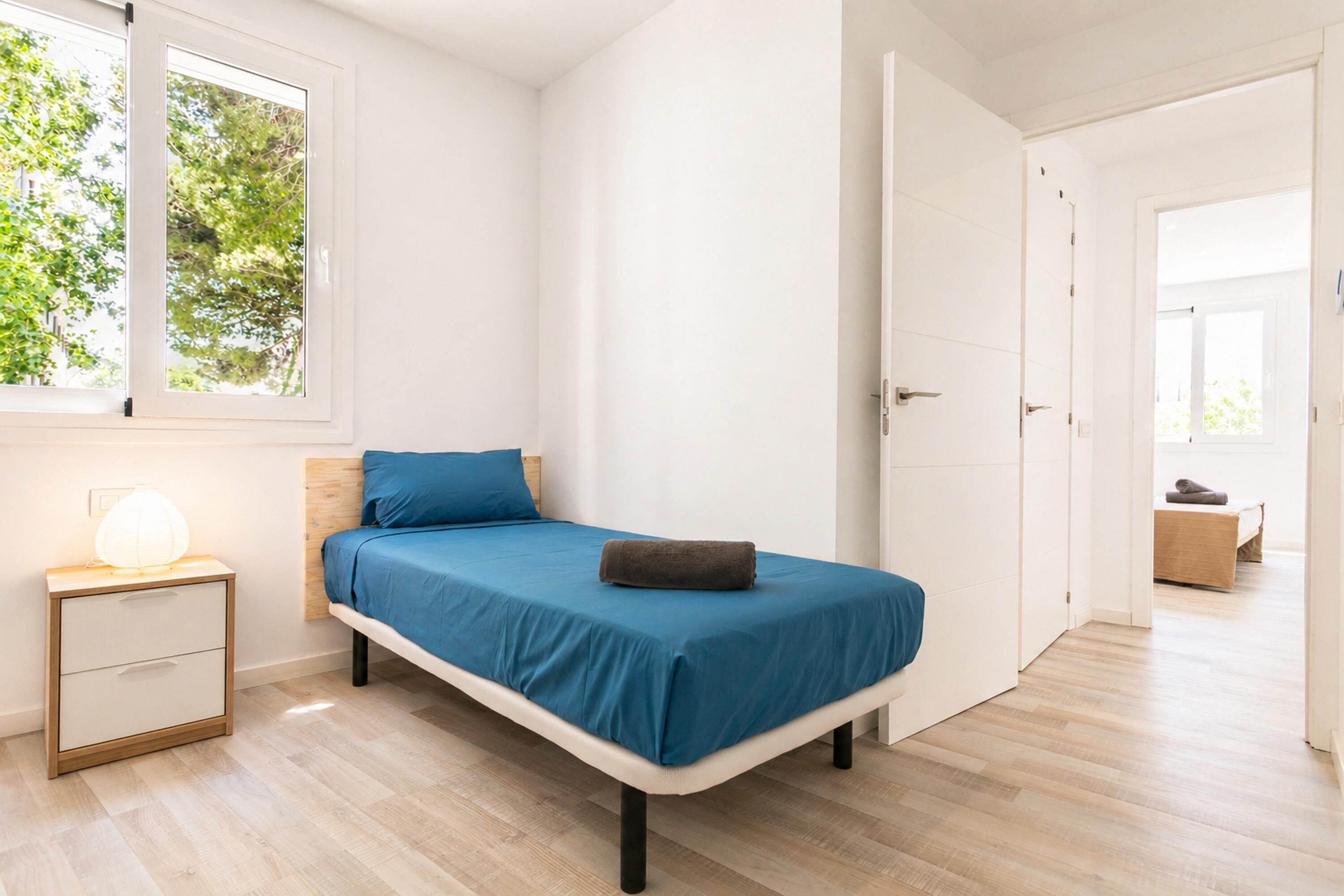 A bedroom with a bed, bedside table, and a window.