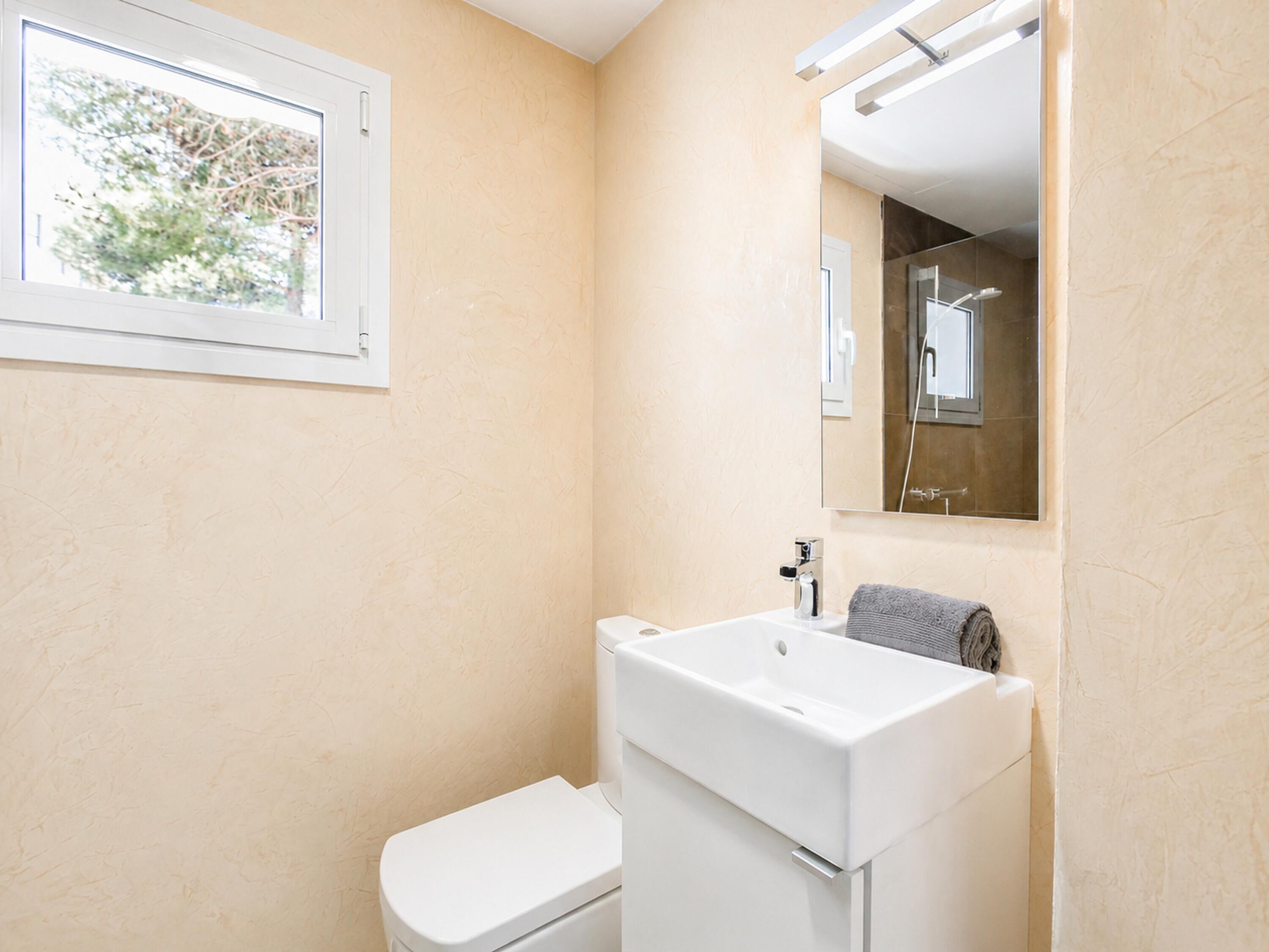 A bathroom with a toilet, sink, and mirror.