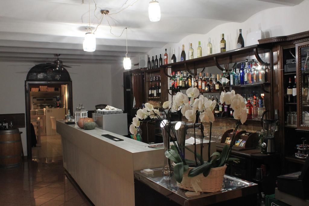 A bar area with a counter, shelves of liquor bottles, and a decorative arrangement of white flowers.