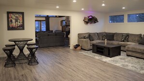 A modern living room with a sectional sofa, a round coffee table, and a dining area with a small table and chairs.