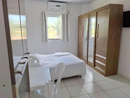Quarto com cama, escrivaninha, cadeira, guarda-roupa e janela.