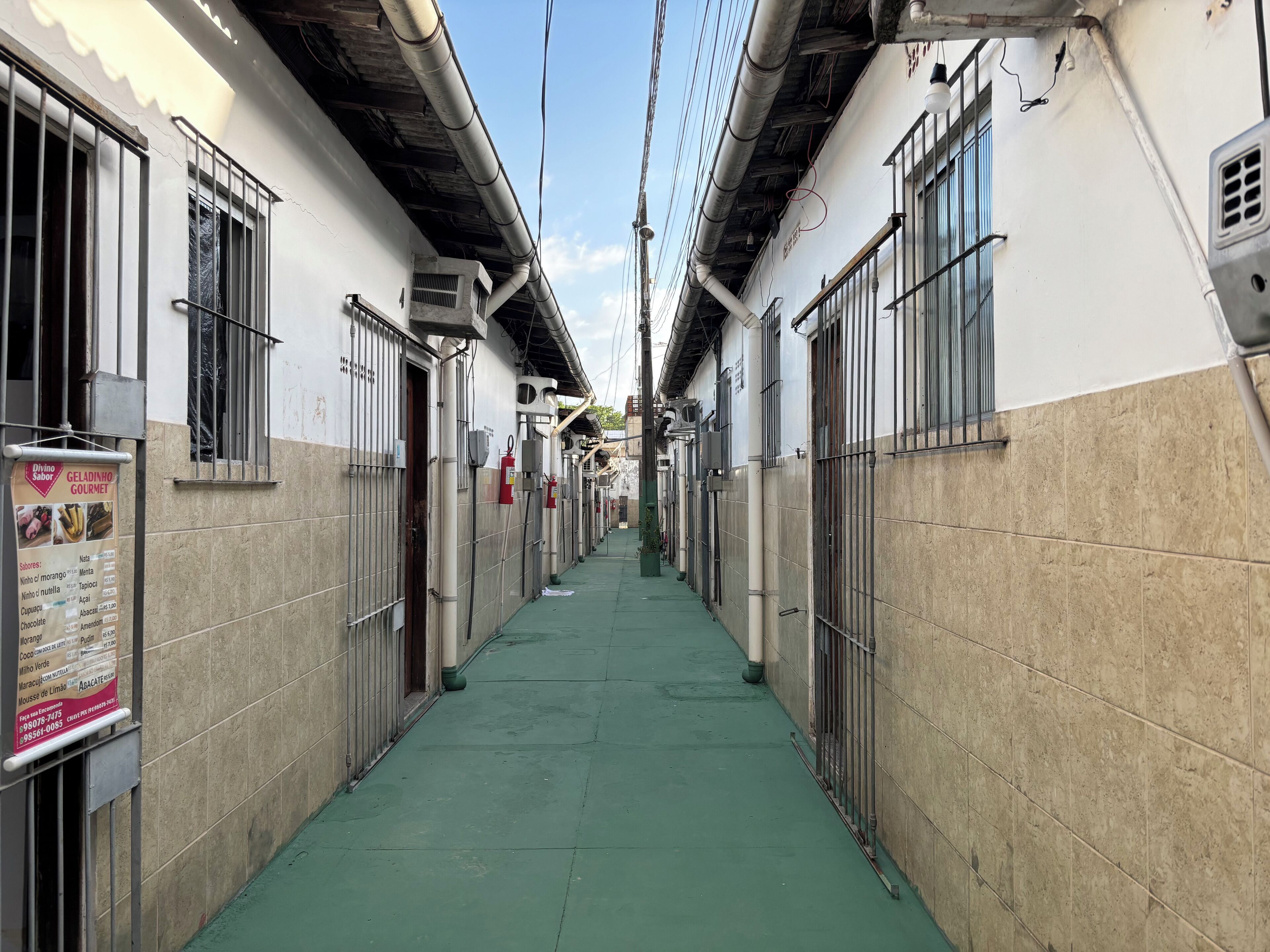 Un couloir étroit aux murs recouverts de carreaux et aux rampes en métal, qui mène à plusieurs portes.