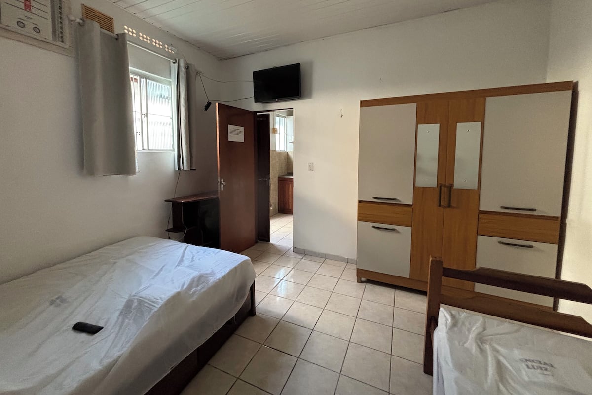 A room with a bed, a desk, a wardrobe, and a television on the wall.
