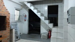 Uma escada estreita conduz a um interior escuro, com um extintor de incêndio e uma gaiola de metal perto dos degraus.