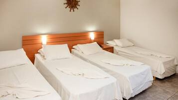 Una habitación de hotel con tres camas individuales, cada una con cubrecama y almohadas blancas.
