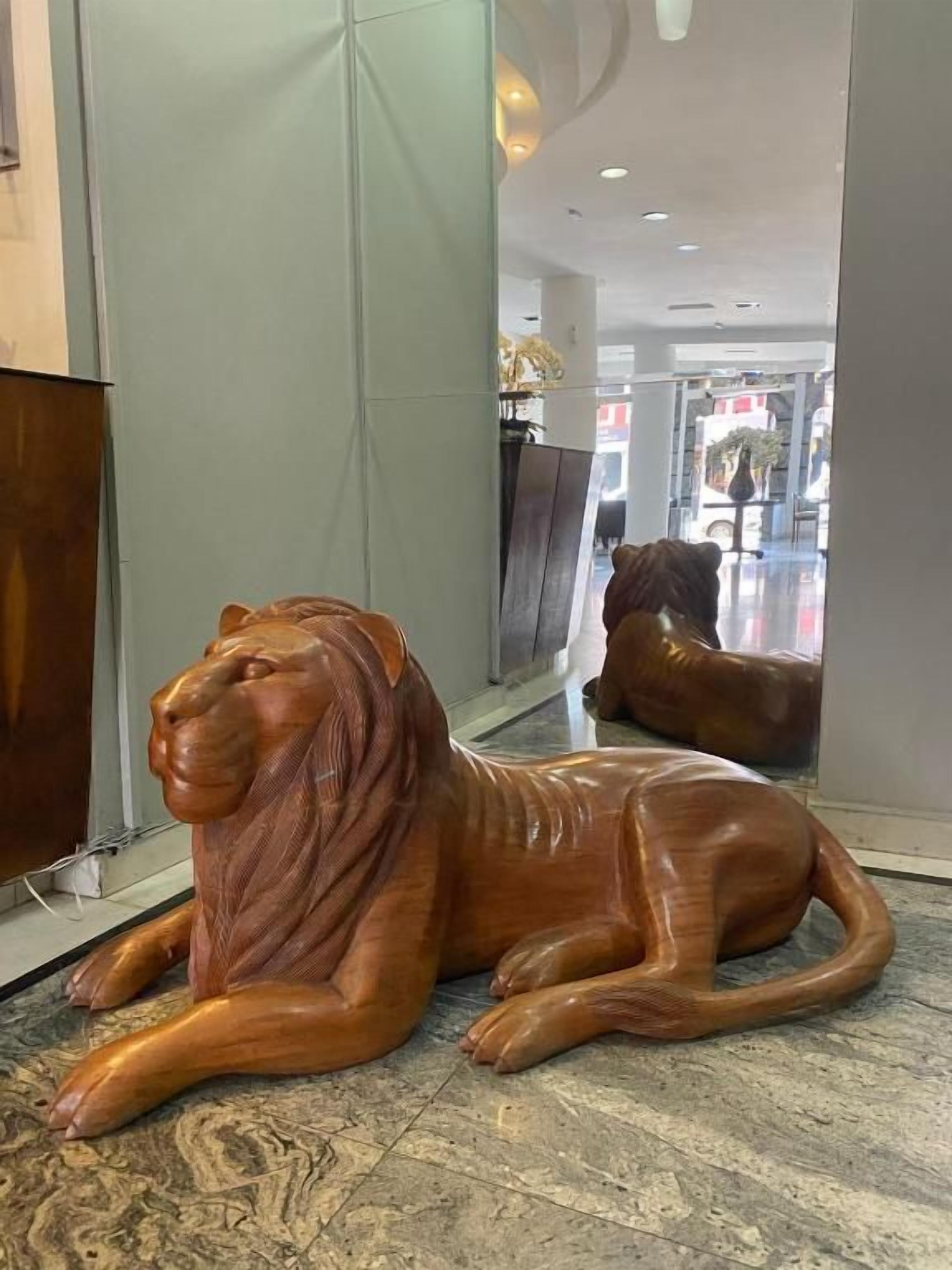 Una escultura de león de madera en un pasillo con suelo de mármol.