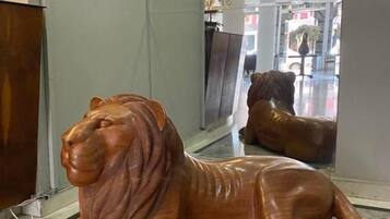 Una escultura de león de madera en un pasillo con suelo de mármol.