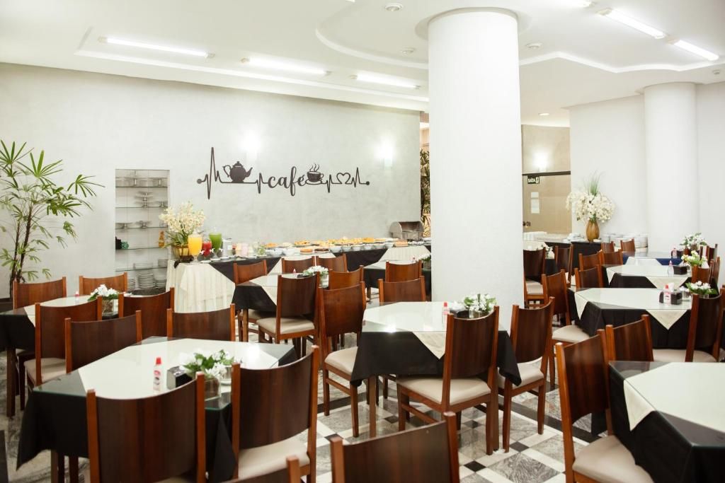 Ein Restaurant mit mehreren Tischen und Stühlen, einer Wand mit Herzschlag-Design und Café-Logo, sowie einem Buffetbereich.