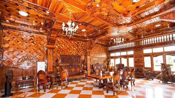 A spacious room with a checkered floor, ornate wooden ceiling, and a chandelier.