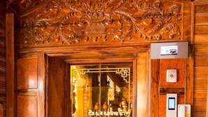 A wooden door with intricate carvings, a glass panel, and a small digital display.