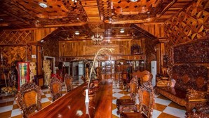 A spacious room with a large wooden dining table, ornate chairs, and a checkered floor.