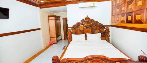 Un dormitorio con una cama grande de madera, cabecera de madera y suelo de baldosas.