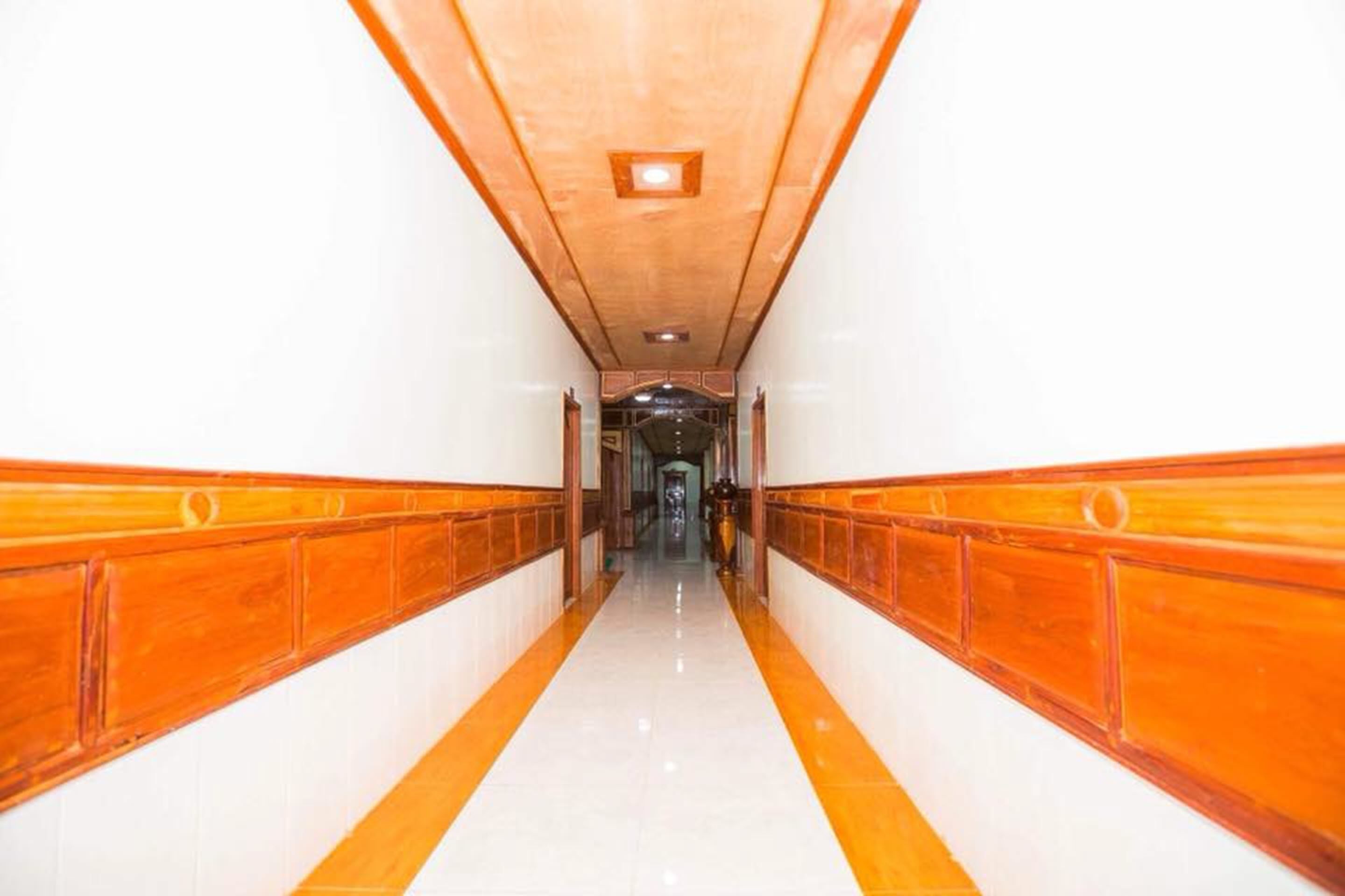 A long, narrow hallway with wooden paneling on the walls and a shiny tiled floor.