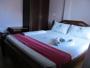 A neatly made bed with a red blanket, white pillows, and a rolled towel. - Diplomat Diani Beach Resort (Diani Beach)
