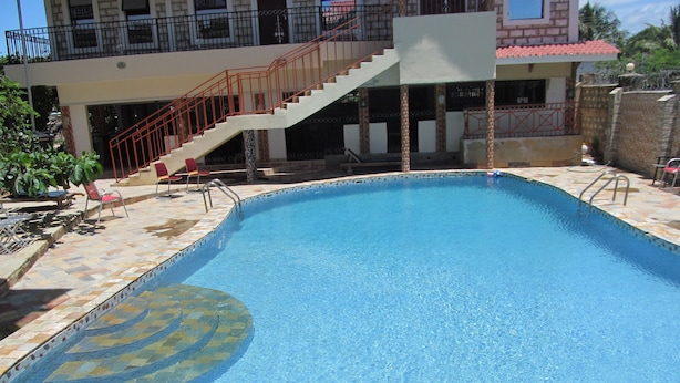 A rectangular swimming pool with a tiled edge and a circular pattern on one side. There are lounge chairs and a staircase leading to an upper level. - Diplomat Diani Beach Resort (Diani Beach)