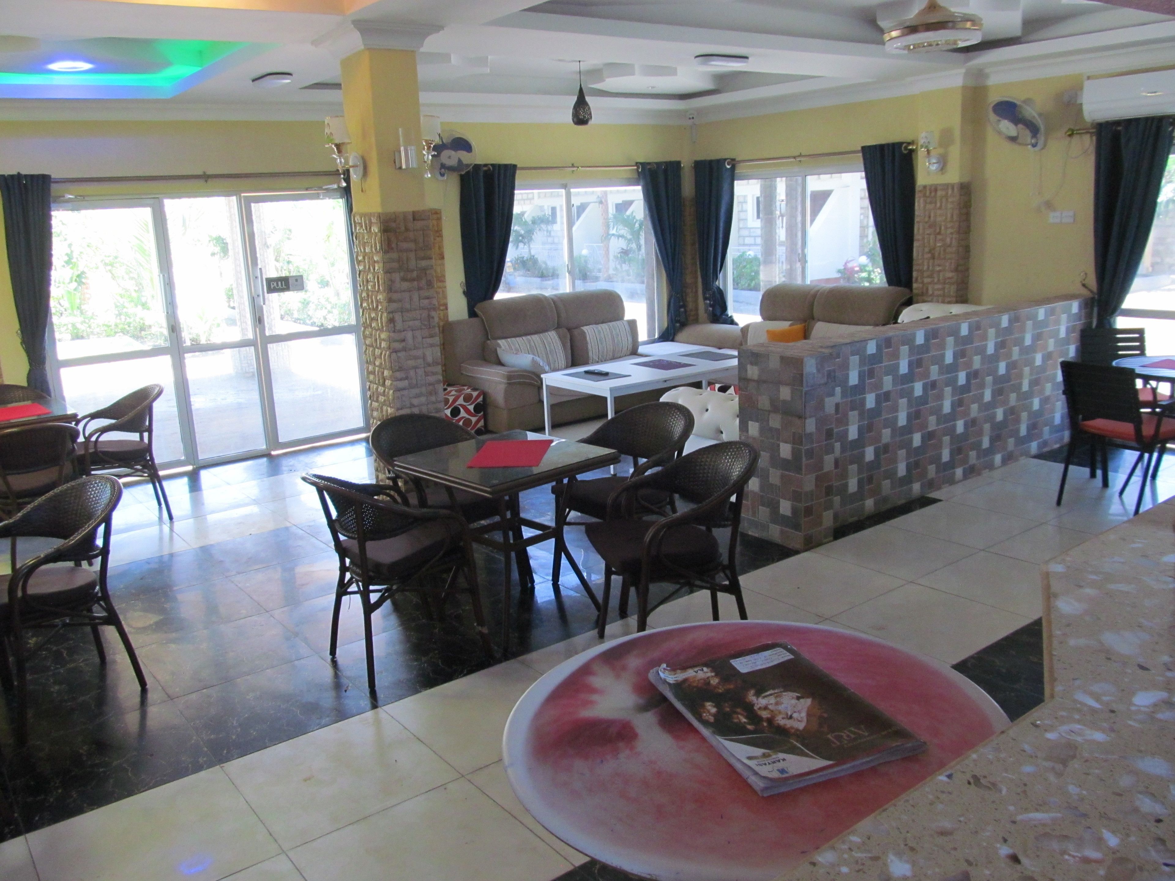 Un restaurante con comedor, bar y zona de estar con sofás y sillas.