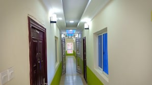 A hallway with green walls, white tiled floor, and a door on the left. - Diplomat Diani Beach Resort (Diani Beach)