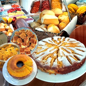 Un bufé con diversos alimentos, incluyendo pan, pasteles y frutas.