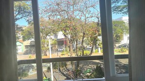 A window view of a street with trees, a bench, and parked cars. - Grande Hotel Amparo (Amparo)