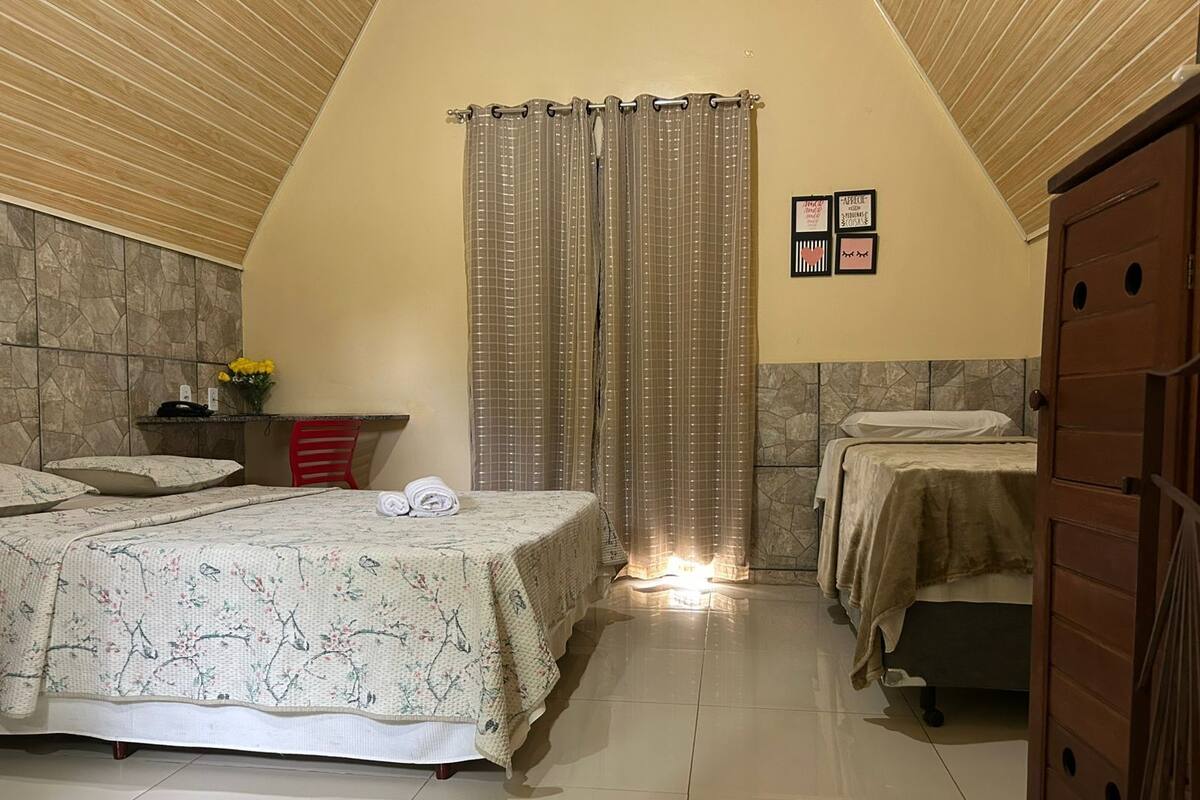 A bedroom with two beds, a stone wall, a wooden ceiling, and a door.