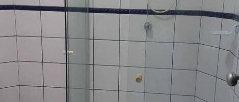 A bathroom with a glass-enclosed shower, white tiles, and a blue stripe.