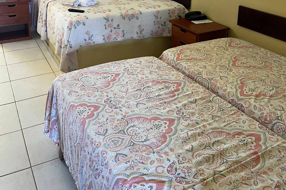 A room with two beds, a nightstand, a desk, and a wall-mounted painting.