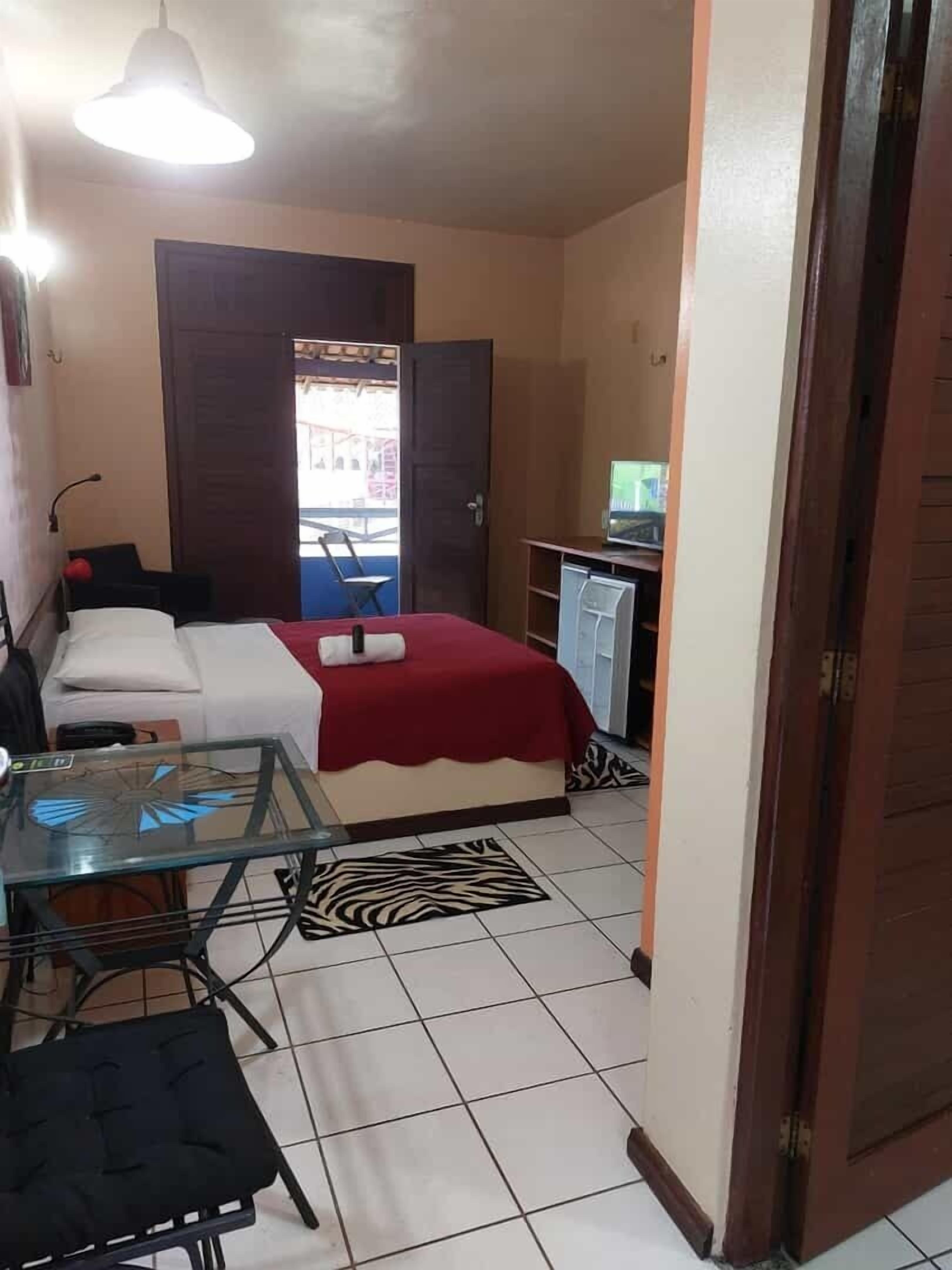 A compact room with a bed, a desk, a chair, and a small table.