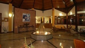 Eine großzügige Lobby mit hoher Holzbalkendecke, einer zentralen Fontäne und einer Sitzecke mit Sofas.