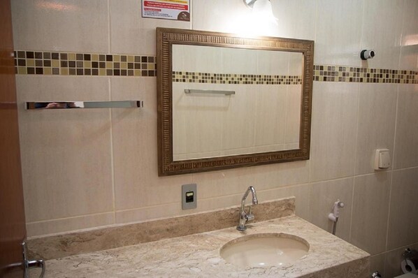Un baño con un espejo grande, un lavabo y un perchero para toallas.