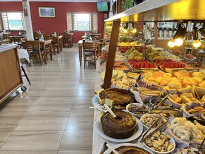 A buffet with various food items and a cake on a table.