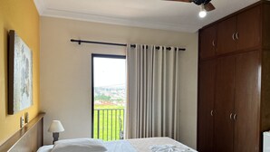 Une chambre d’hôtel comprenant un lit, une table de chevet, une lampe, une vue sur l’extérieur et une armoire en bois.