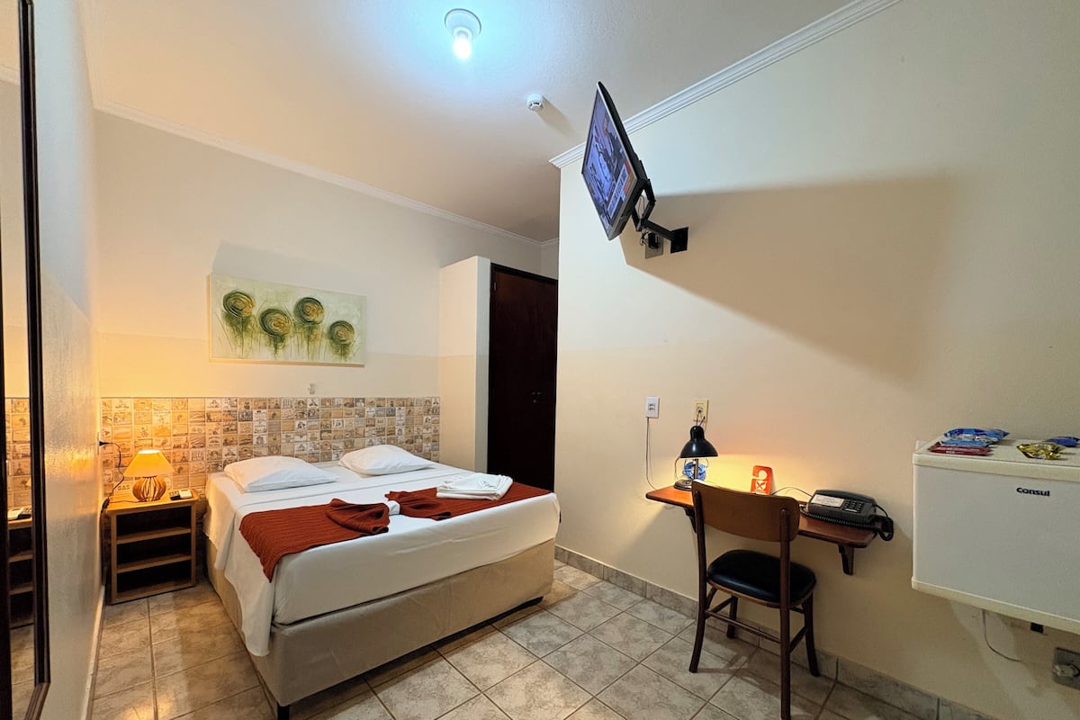 Une chambre d’hôtel comprenant un lit, un bureau avec une chaise, une télévision et un réfrigérateur.