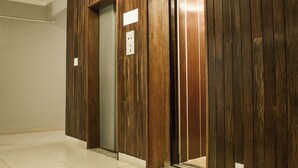 An elevator with wooden paneling and a tiled floor. - Lider Hotel Ituiutaba (Ituiutaba)