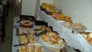 Una mesa de buffet con diversos productos de panadería, como pan, pasteles y una rosquilla.