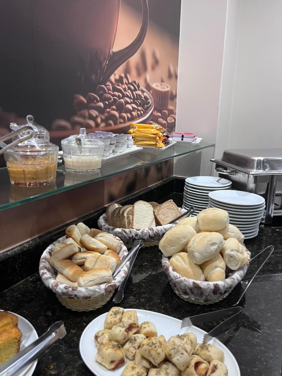 Un bufé con diversas opciones de comida, como pan, bollería y una estación de café.