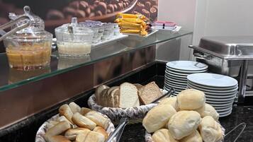 Un bufé con diversas opciones de comida, como pan, bollería y una estación de café.